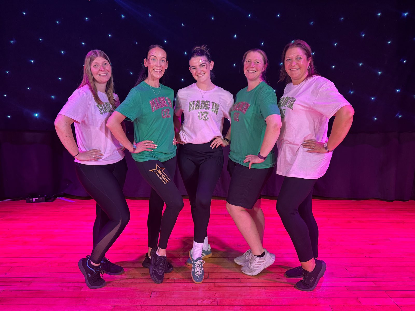 Members of the McCaw team smiling together on a pink-lit stage