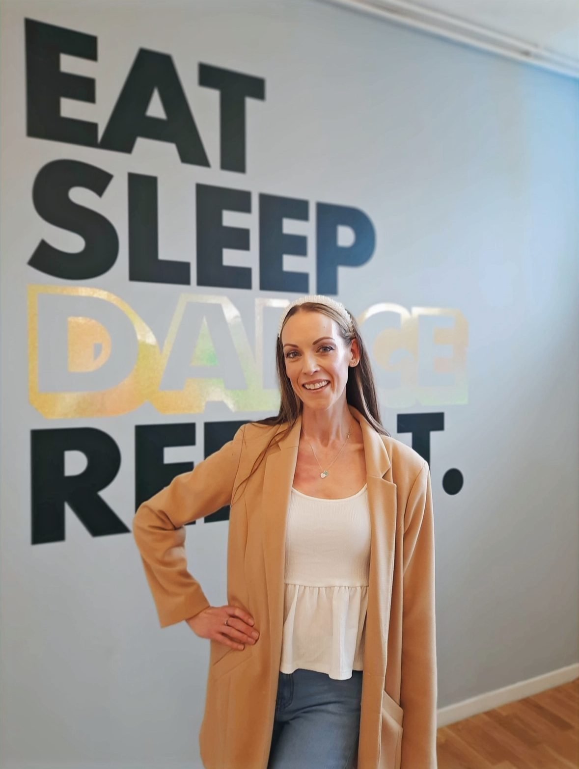 Charlotte Ormerod in the studio in front of an 'Eat, Sleep, Dance, Repeat' wall